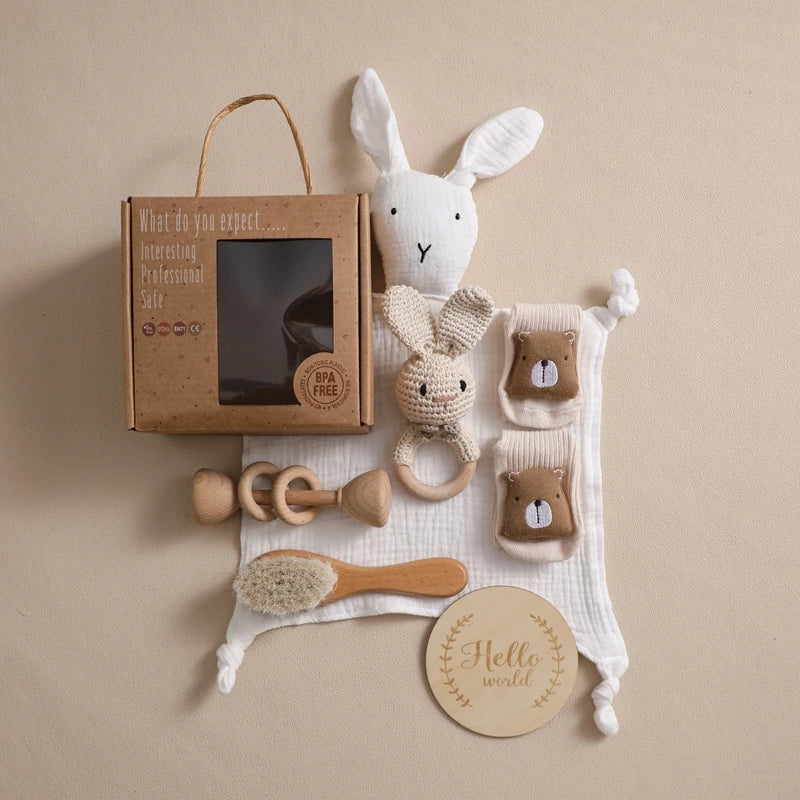 Baby toys and items including a rabbit plush toy, wooden rattle, and baby brush on a beige background.