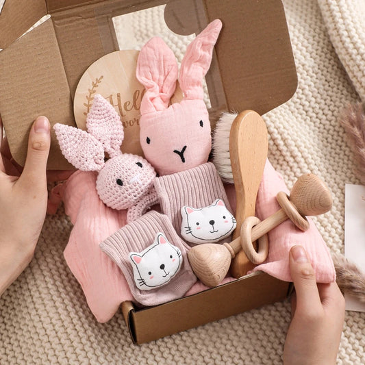 Baby toy set with plush toys and wooden tools in a box on a textured surface