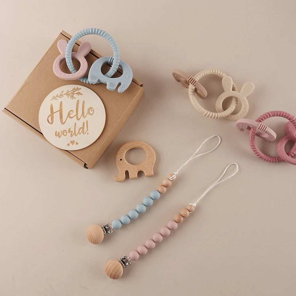 Baby teething toys and pacifier clip with 'Hello world!' sign on a beige background